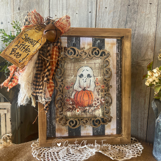 Whimsical ghost with pumpkin 8x10 wood frame canvas decor with distressed black cream striped shiplap background ornate laser-cut wood overlay black buffalo check orange ribbon bow rusty jingle bell and Sweet Little Boo hand-lettered tag by Country Charm by Tracy