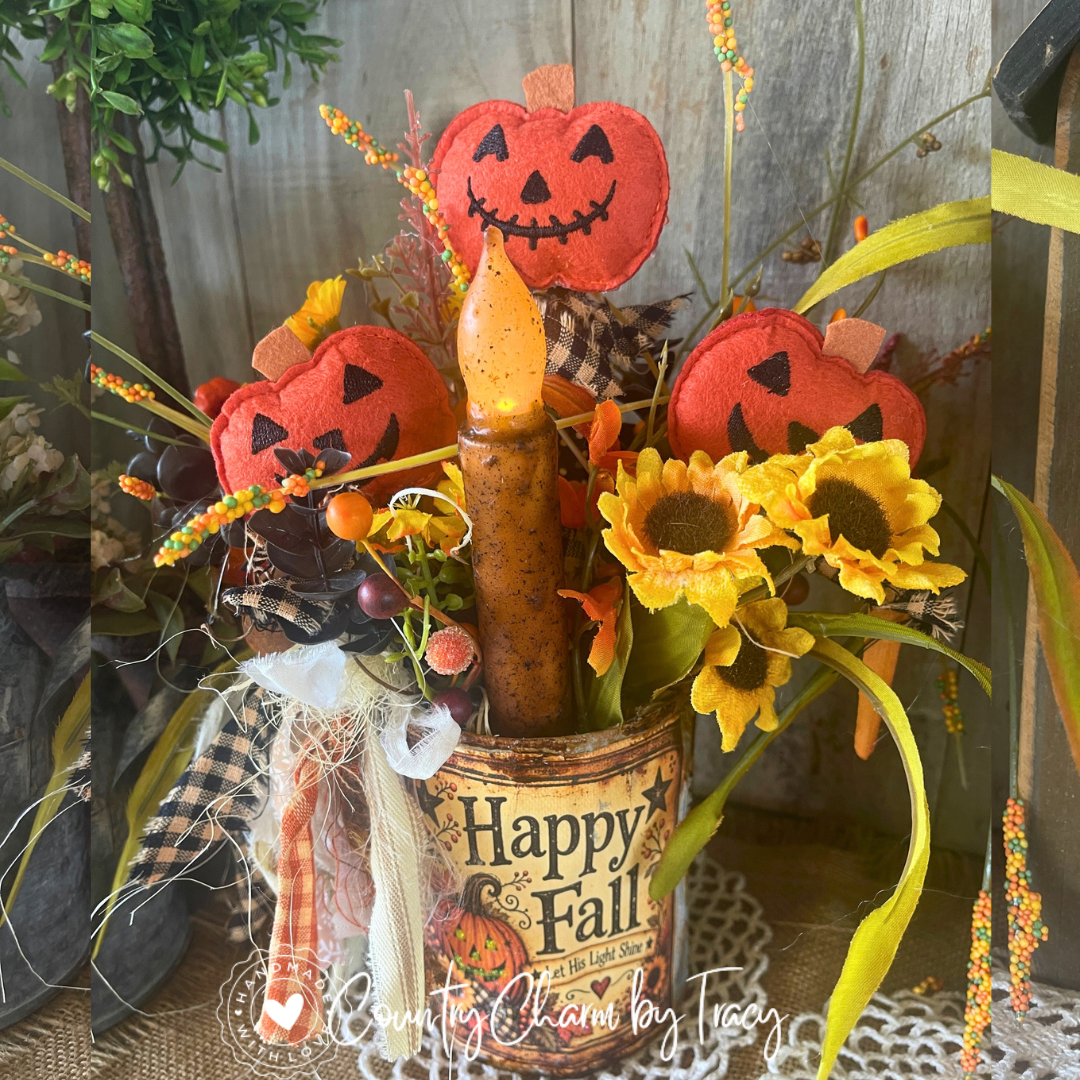 Close-up of three felt pumpkins, flickering primitive candle and autumn florals in Happy Fall tin can decor