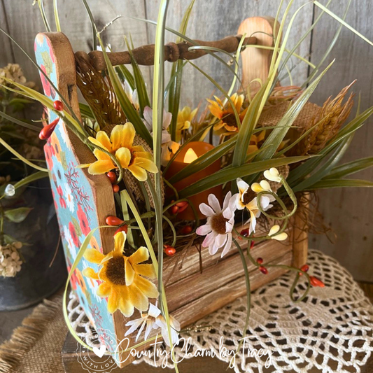 Rustic fall wooden caddy with turquoise floral cutting board accents, daisies, greenery, pip berries, and a lighted candle.